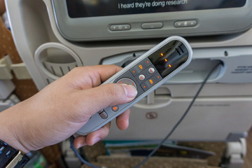 Passenger man hand holding remote control of airplane Entertainment on board