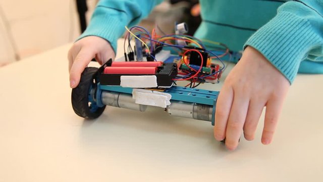 Robotics technology and STEM education class concept: Boy adjusts his robot. Programs for learning coding study in computer laboratory in school for kid