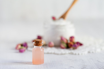 Concept of natural organic ingredients in cosmetology. Extract of rose for moisturizing, delicate skin nutrition, pore narrowing and anti-cellulite effect. White background, copy space