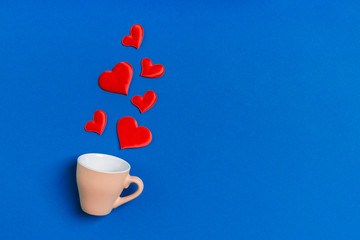 Top view composition of red hearts falling out from a cup on colorful background with copy space. Romantic relationship concept. St Valentaine's Day