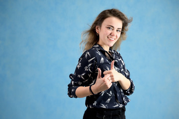 Fototapeta na wymiar Concept woman in a dark blouse smiling talking. Portrait of a model girl with excellent makeup with curly hair and good teeth in the studio on a blue background.