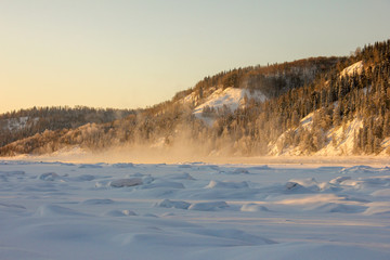 snow-covered hills, evergreen trees on the slopes, in the sunset. Lots of snow and frost trees. 