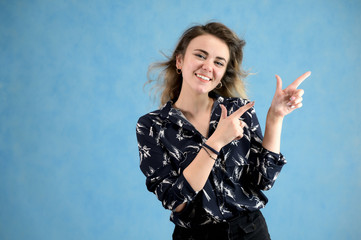 Concept woman in a dark blouse smiling talking. Portrait of a model girl with excellent makeup with curly hair and good teeth in the studio on a blue background.