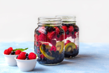 Fototapeta na wymiar Fresh cool detox drink with raspberries, blueberries and kiwi in mason jar mug. Lemonade in a glass with a mint. The concept of proper nutrition and healthy eating. Fitness diet. Copy space for text
