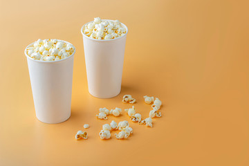 Fresh popcorn in white box on a orange background. Cinema snack concept. The food for watching a movie and entertainment. Copy space for text, top view, flat lay.
