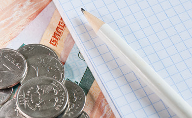 Russian money (rubles coins and bills), a blank sheet of a notebook (squared) and a pencil