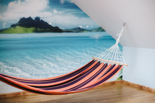 Hammock inside a room with a panorama picture of tropical island on the wall