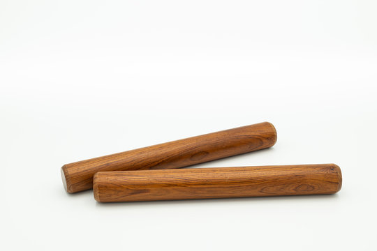 A pair of wooden claves lying on a white underground