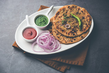 Fototapeta na wymiar Onion Parotha / Pyaj parantha / kanda paratha served with tomato ketchup and green chutney. selective focus