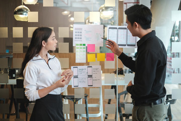 Obraz premium Two Asian application designers work together to brainstorm, outline, and develop mobile applications.