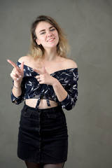 Vertical portrait of a girl model with excellent makeup with good teeth in the studio on a gray background. Concept woman in a dark suit smiles and talks.