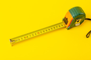 Repair, construction and tools background. Measuring tape on a yellow background. Copy space