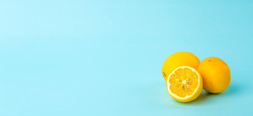 Naklejka premium Summer and vitamins background banner. Lemon on a blue background, minimal food concept
