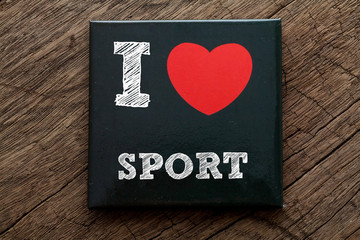 I Love Sport written on black note with wood background