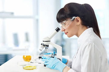 Girl laboratory assistant in a white uniform and goggles