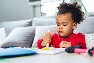 African American little girl drawing with colored pencils.