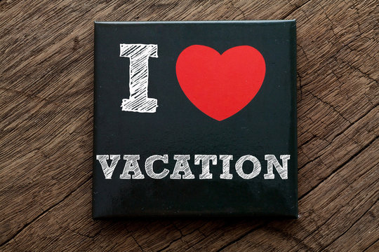 I Love Vacation written on black note with wood background