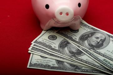 Piggy bank with dollars on red background. Selective focus.