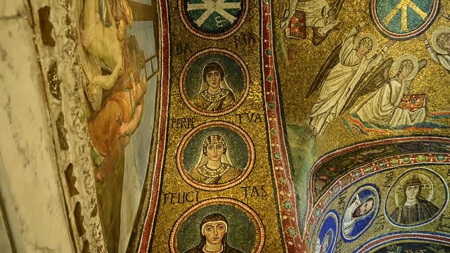 Ravenna, Italy, December 2019. Inside the Chapel of Sant'Andrea we are struck by the colors and beauty of the mosaics. Tilt movement on the arch with the half busts of the saints.