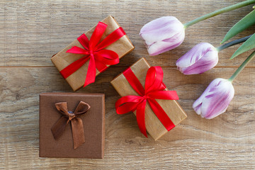 Gift boxes with tulip flower on the wooden background.