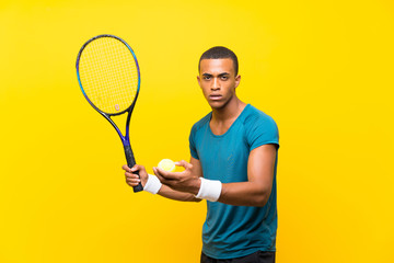 Afro American tennis player man over isolated yellow background