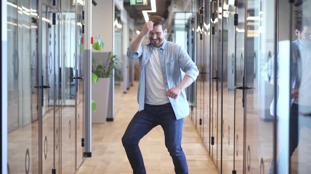 Excited young man employee celebrating business success.