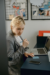 Pretty young woman holding pencil at workplace