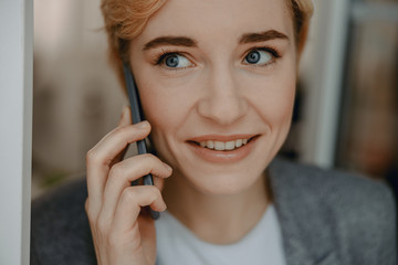 Smiling young lady having conversation on smartphone