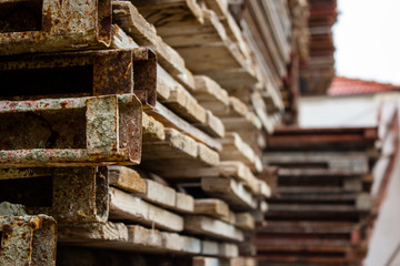 Industrial wooden pallets stack. Industrial wooden beams in the factory warehouse laid in neat rows. Long shot of neat rows industrial wooden pallets stack on a construction site.