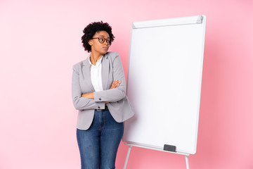 African american business woman giving a presentation on white board over isolated pink background making doubts gesture while lifting the shoulders