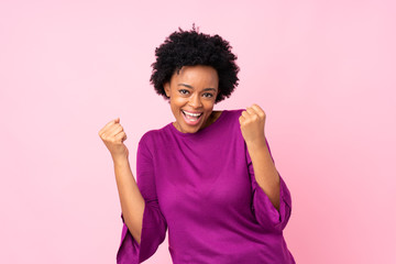African american woman over isolated pink background celebrating a victory