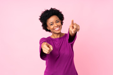 African american woman over isolated pink background points finger at you while smiling