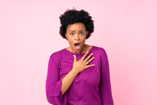 African american woman over isolated pink background surprised and shocked while looking right