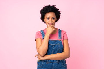 African american woman with overalls over isolated pink background thinking an idea