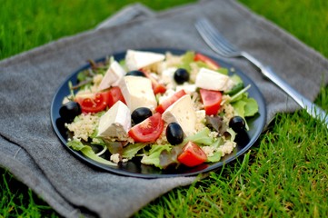 Fresh salad with lettuce, black olive, tomato, arugula, cous-cous and camembert cheese
