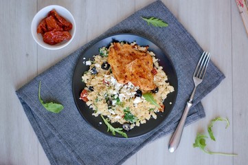 Low carb food chicken fillets white cauliflower rice with dryed tomato, black olive, arugula and cheese