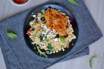 Low carb food chicken fillets white cauliflower rice with dryed tomato, black olive, arugula and cheese