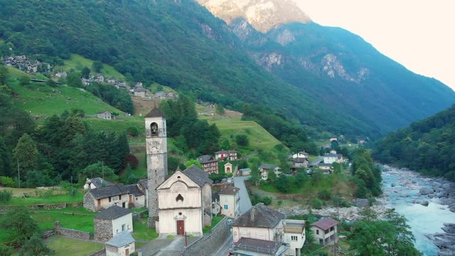 Revealing shot of a church and the town Lavertezzo, next to a blue water river, Switzerland