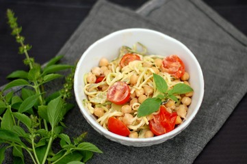 Creamy zucchini spaghetti in sauce with chickpeas,tomato and cheese