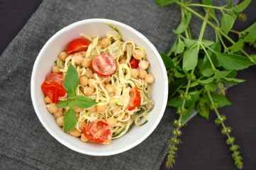 Creamy zucchini spaghetti in sauce with chickpeas,tomato and cheese