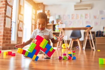 Beautiful african american toddler playing with building blocks smiling at kindergarten