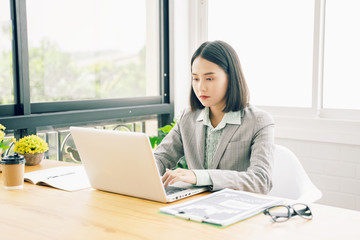 Asian young businesswoman working with laptop in coffee shop cafe while drinking coffee ,technology or startup business concept, modern office or living room copy space