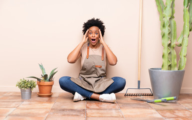 Gardener woman sitting on the floor with surprise expression