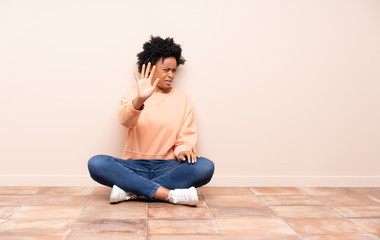 African american woman sitting on the floor nervous stretching hands to the front