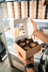 Male hands holding box with food in store