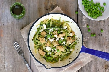 Zucchini spaghetti with pea, chicken meat and cheese on pan