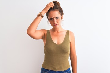 Young redhead woman wearing a bun over isolated background confuse and wonder about question. Uncertain with doubt, thinking with hand on head. Pensive concept.