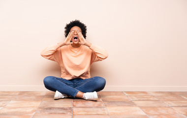 African american woman sitting on the floor shouting and announcing something