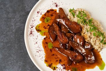 Baked lamb tongues with spicy bulgur porridge in a white plate