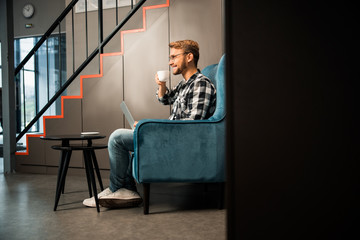 Young handsome man drinking coffee indoors and smiling